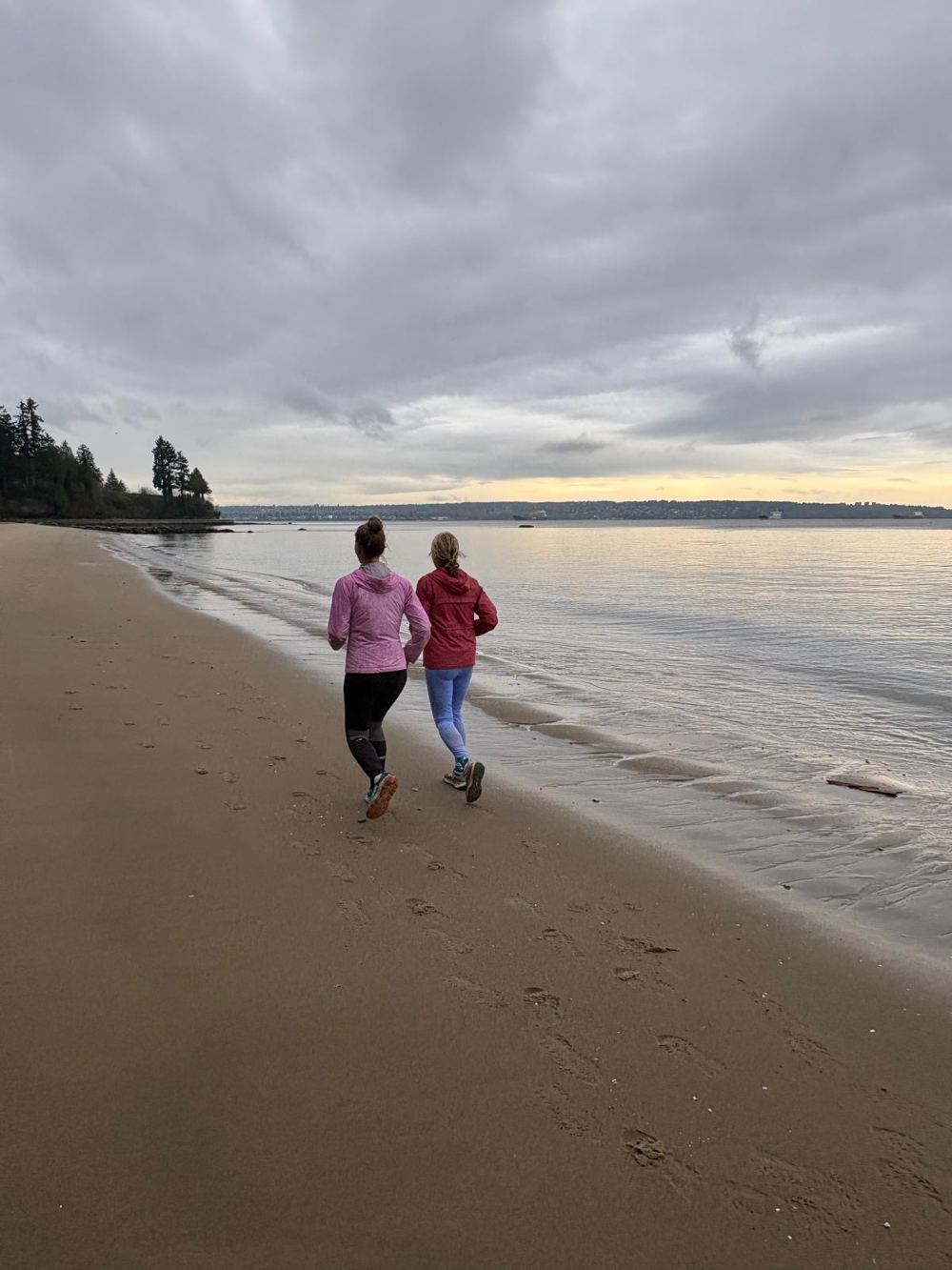 Two runners on the sand at the water's edge